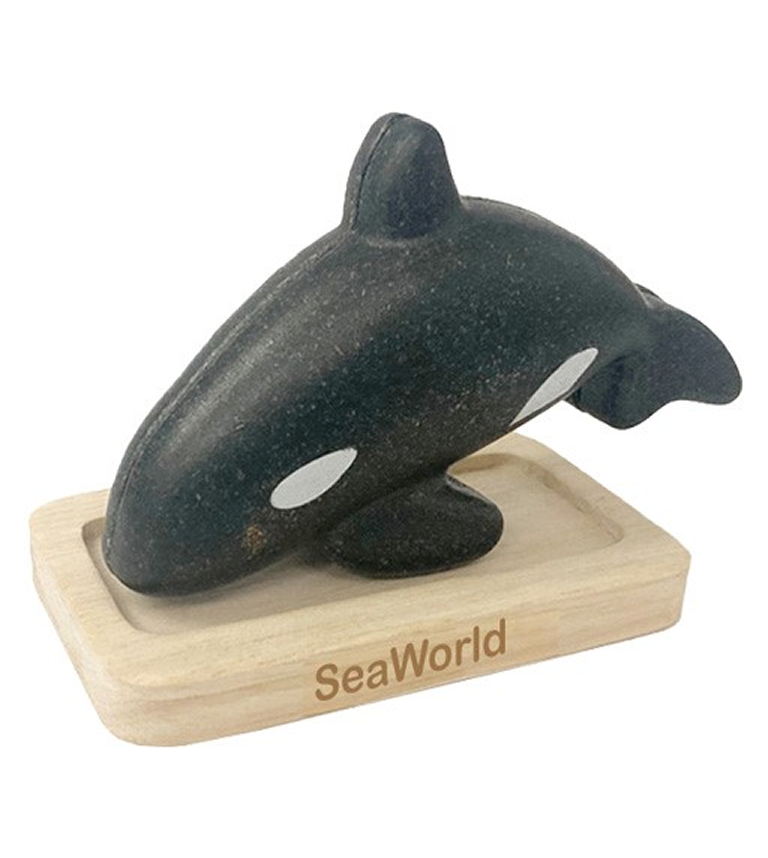 A toy orca whale on top of a wooden block.