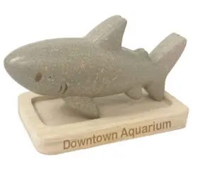 A wooden shark toy with the words downtown aquarium on it.