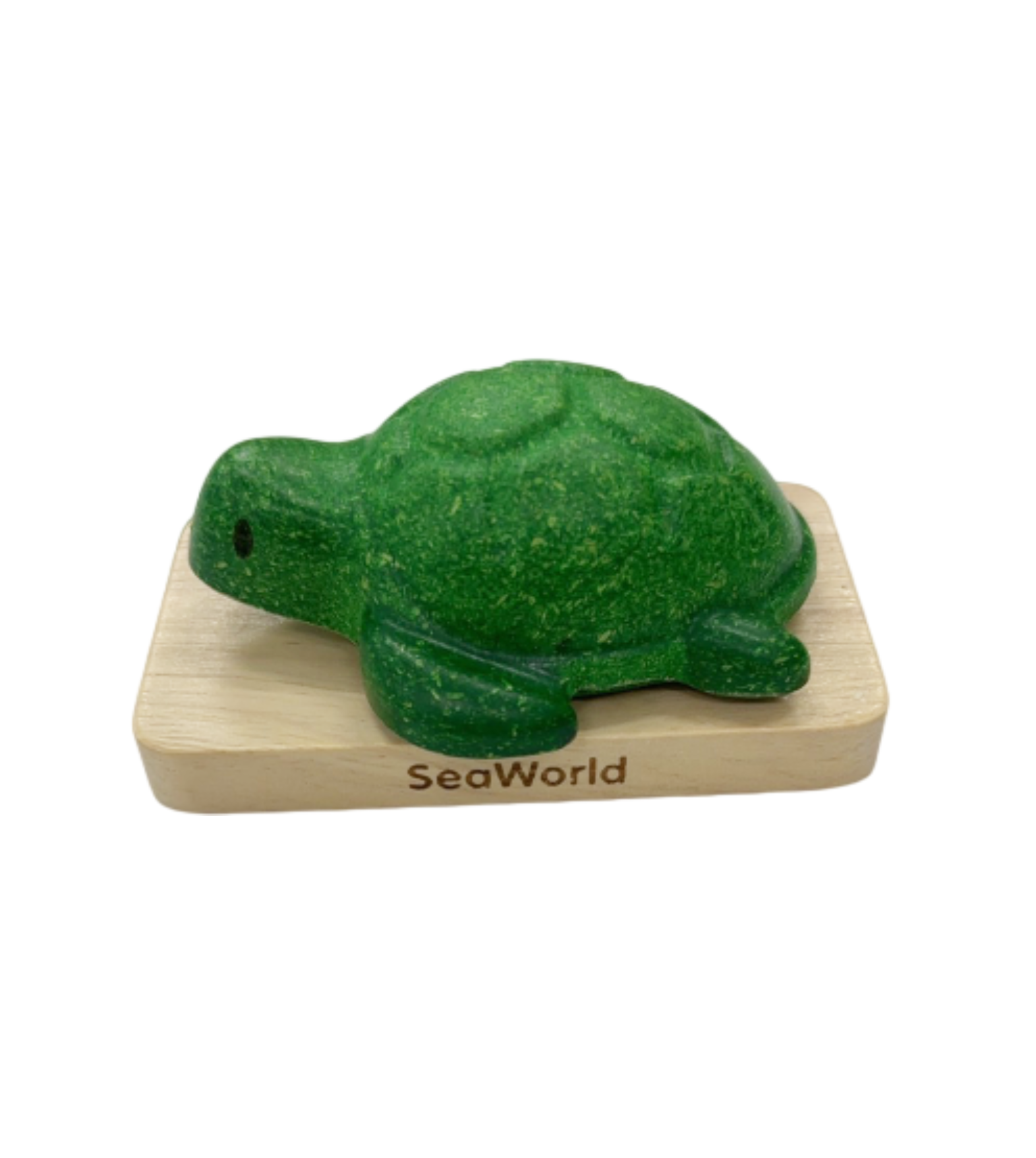 A green turtle is sitting on the wooden block.